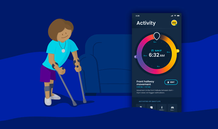 A woman with crutches is smiling wearing a nomo tag on a lanyard. Next to her, a screenshot of the nomo app has the time dial with “6:23am” and a status update underneath that reads “Front hallway movement – 11:35pm – 7:25pm.”