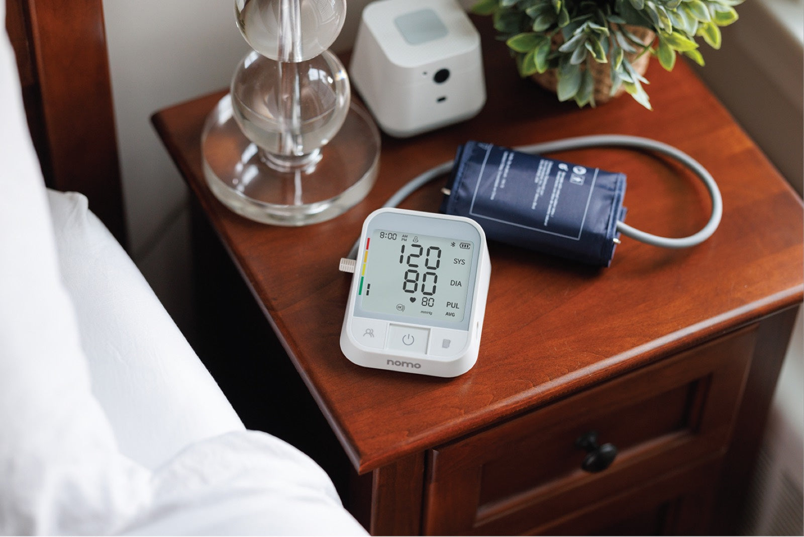 A woman checks her blood pressure with the Nomo monitor at home