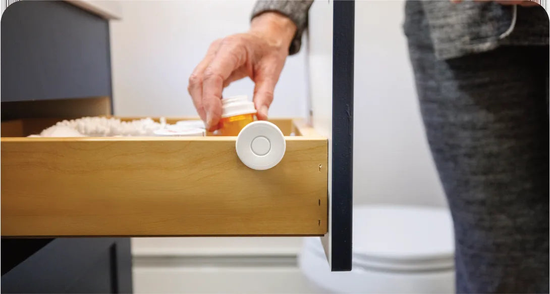 A hand reaches for a pill bottle in a drawer with a Tag on its front