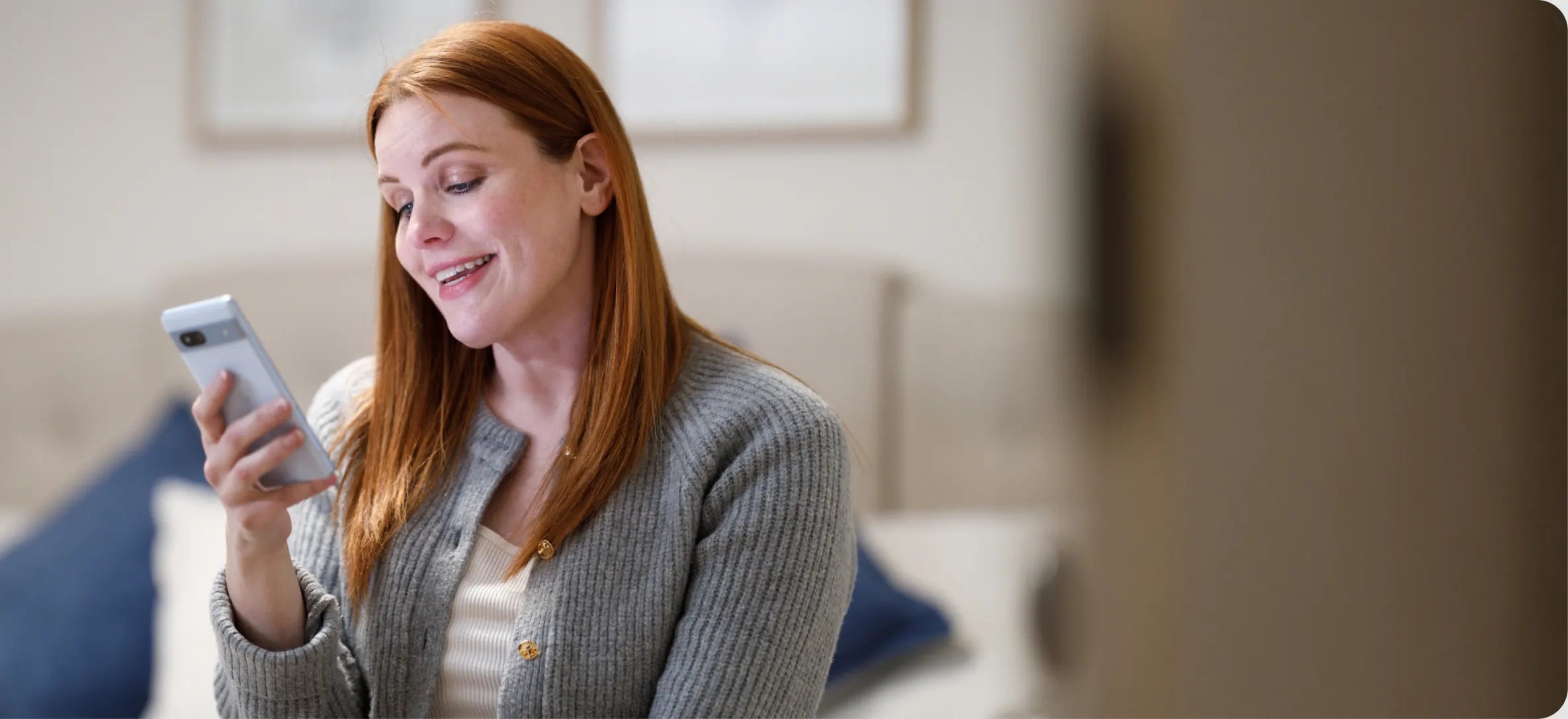 A woman smiles as she looks at her phone