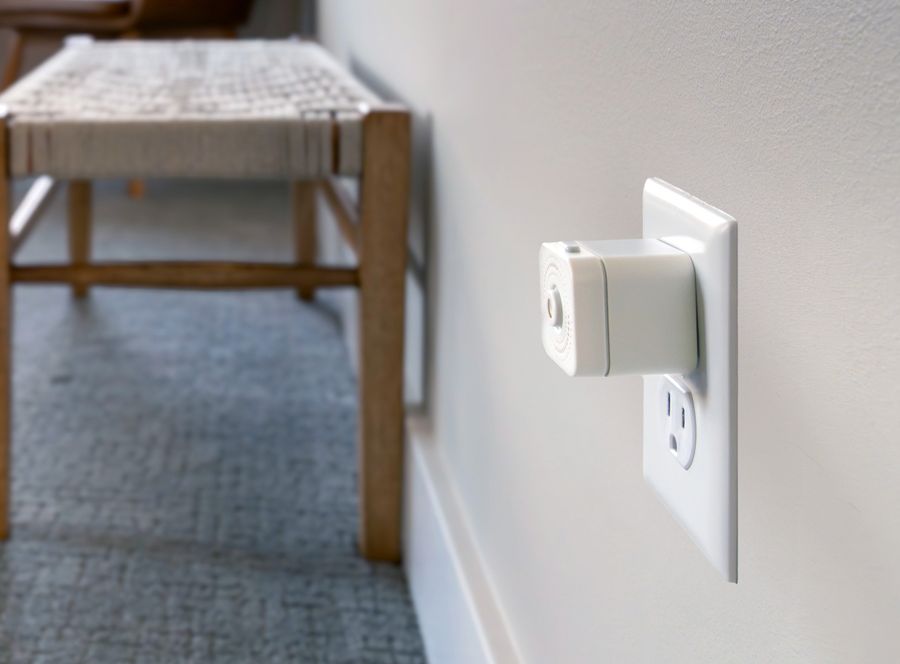 A Nomo Satellite plugged into a wall outlet beside a bench