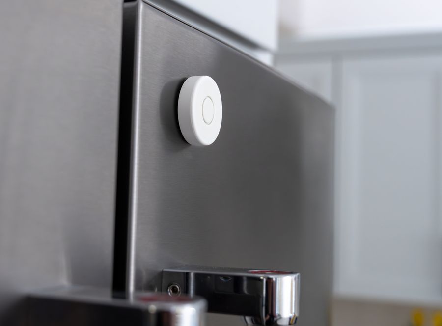 A Nomo Tag stuck to the side of a stainless steel refrigerator door
